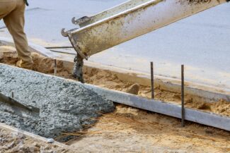 Industrial workers pouring fresh concrete on reinforced cement sidewalk